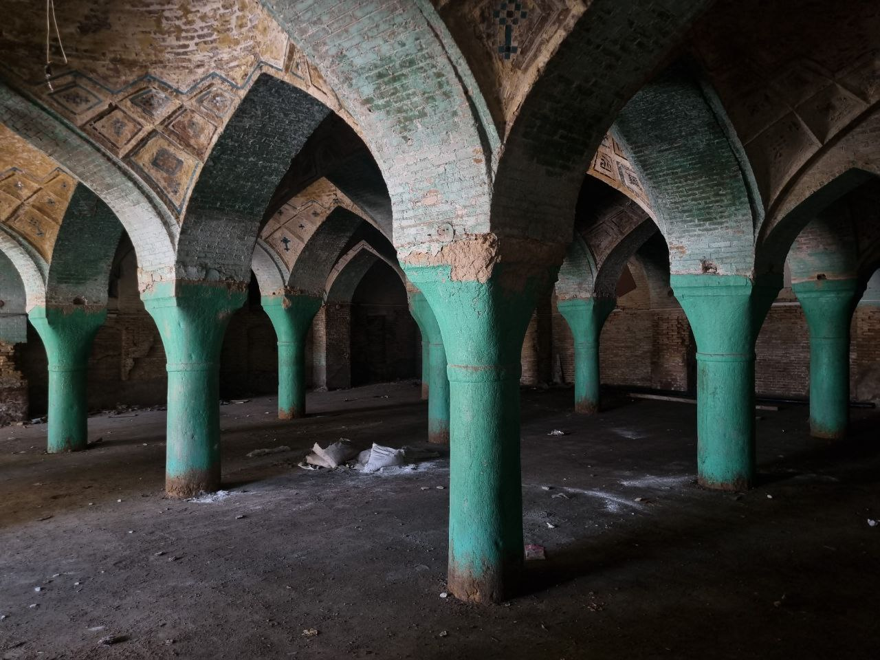 A mosque in Shiraz’s old quarter, remembered as abandoned — green-painted columns and brick vaults.