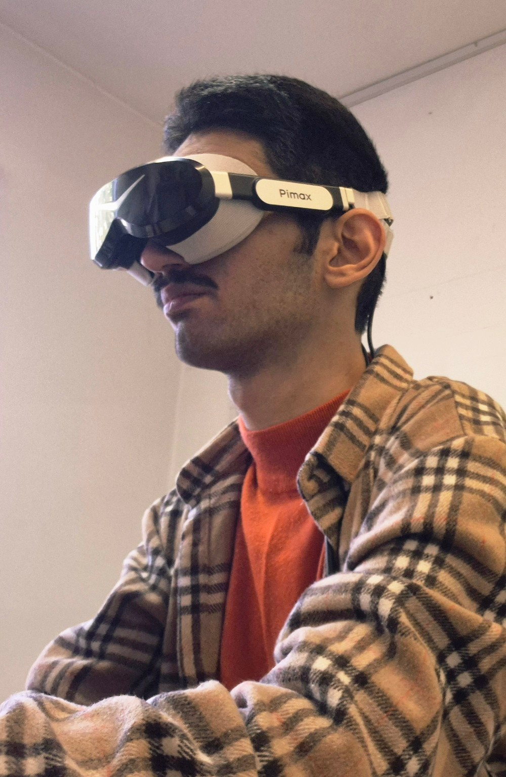 Kiarash testing a Pimax VR headset, in a checked shirt and red jumper