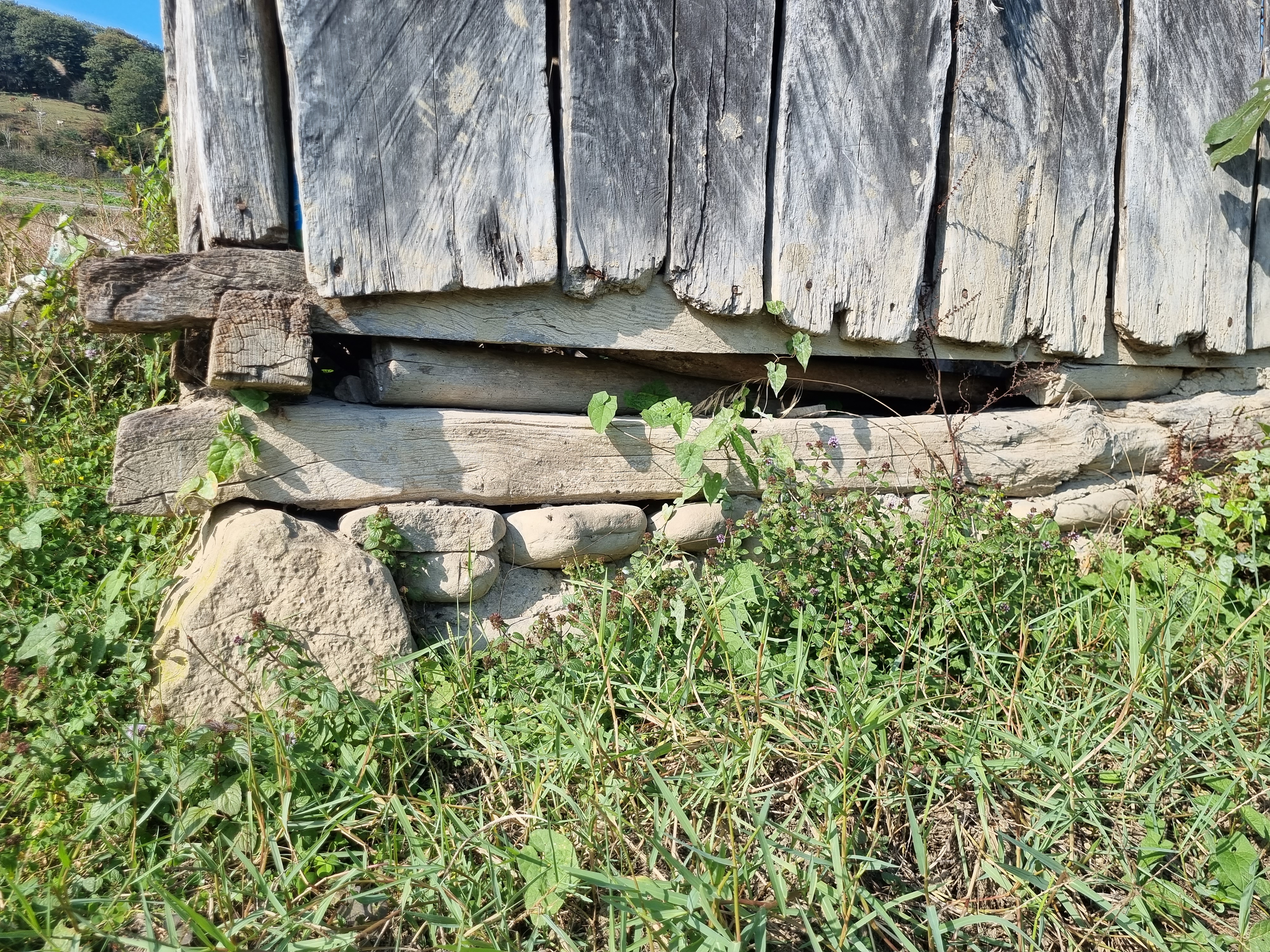 Timber sill and stacked stone bearing below vertical boards
