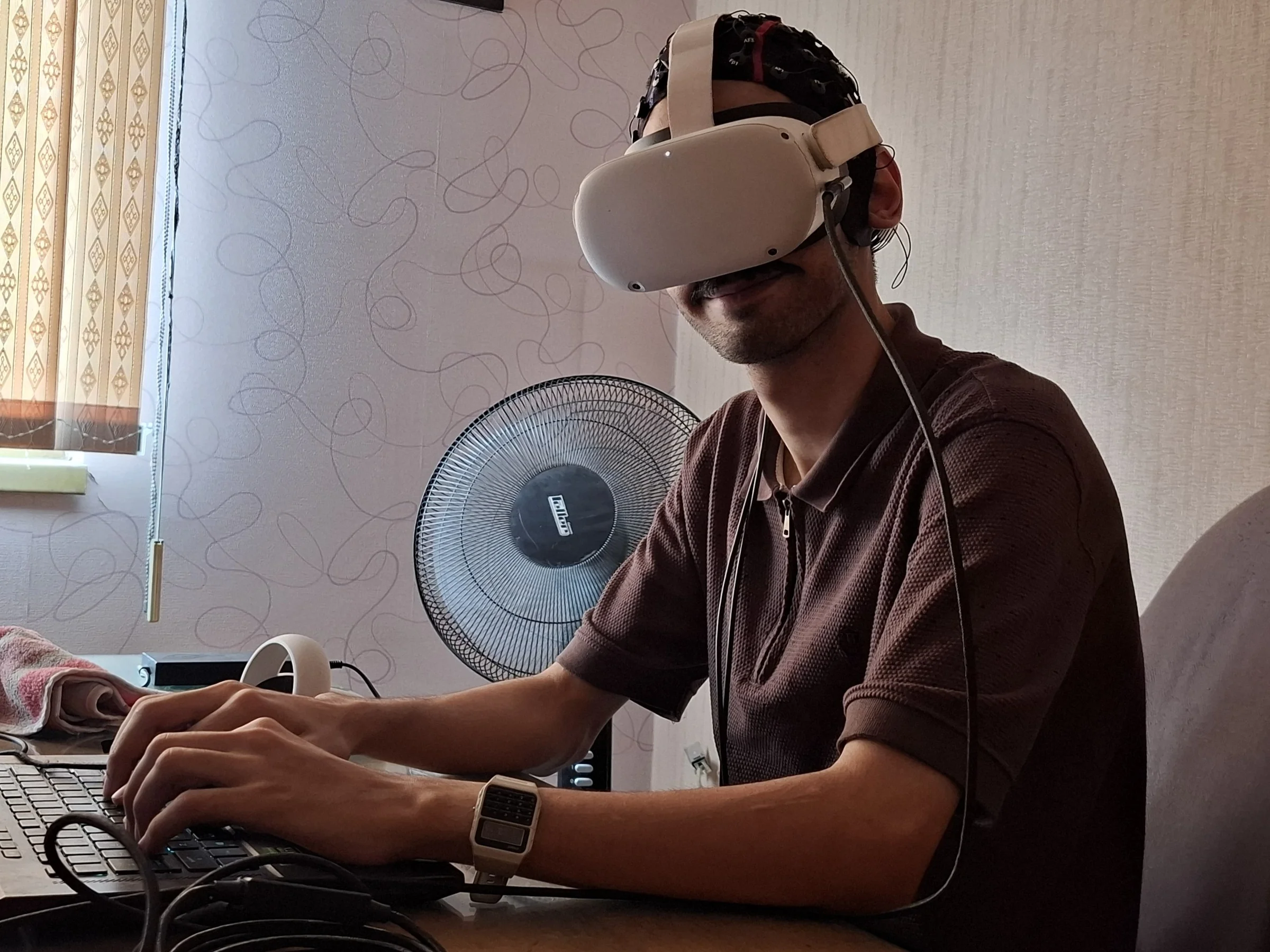 Kiarash wearing EEG and VR while working, photographed in August 2026